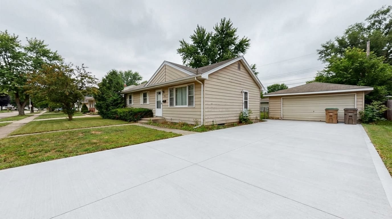 Freshly poured driveway in front of the same suburban home after replacement
